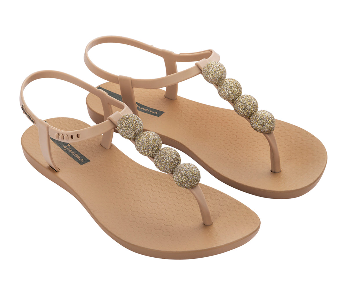 Angled view of a pair of beige Ipanema Disco sandals with straps and 4 glitter balls on top strap.