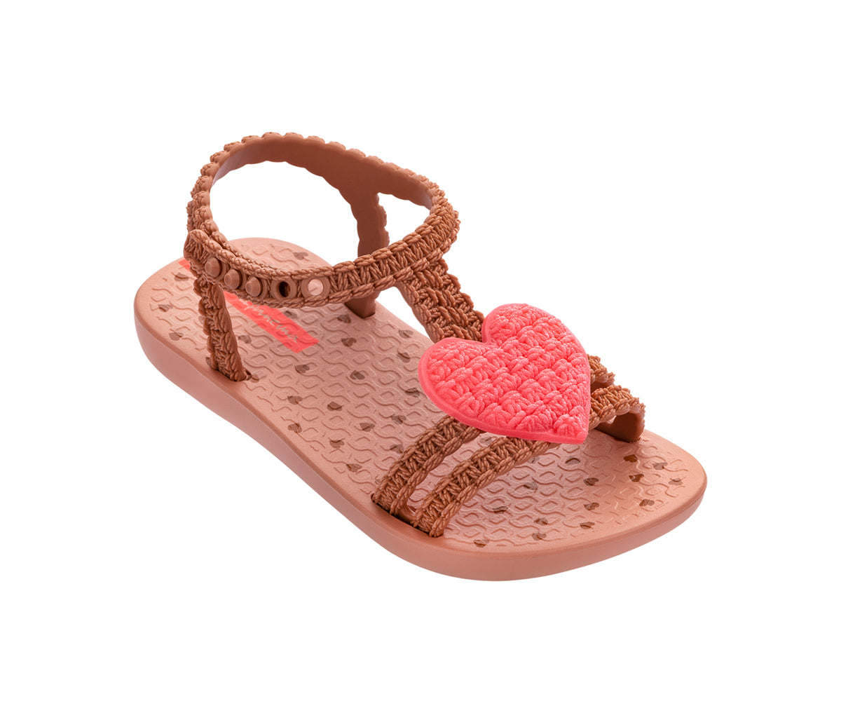 Angled view of a beige My First Ipanema Sandal with straps and a crochet pink heart on top.