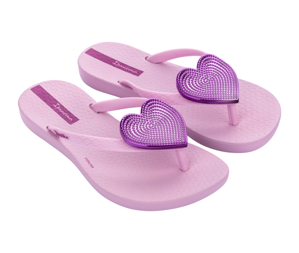 Angled view of a pair of pink Ipanema Wave Heart kids flip flops with a metallic pink heart on top.