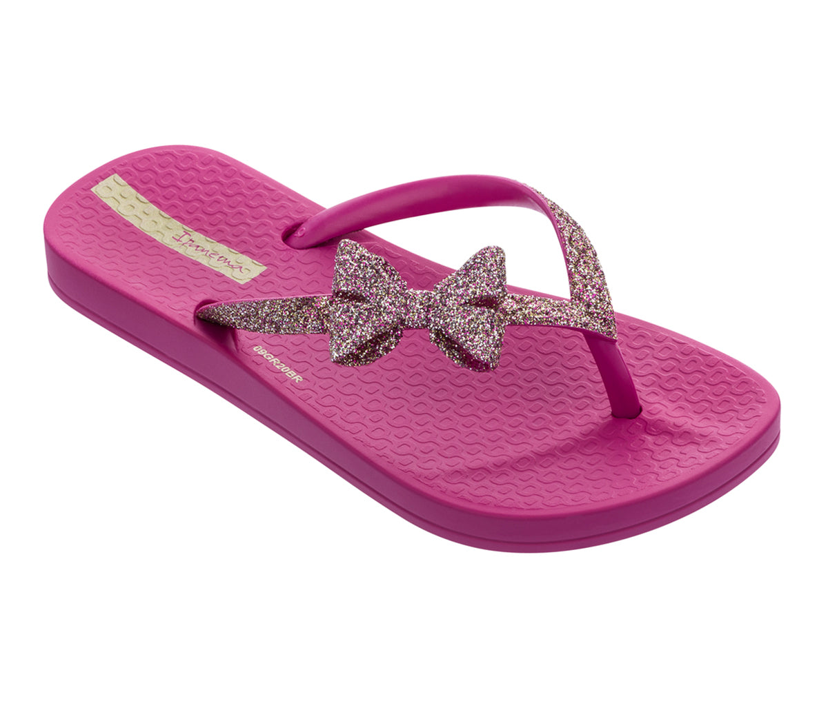 Angled view of a dark pink Ipanema Ana sparkle kids flip flop with a glitter strap and bow.